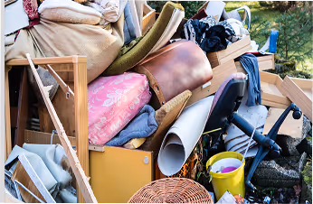 Großer Müllhaufen mit Möbeln, Kissen, einem Bürostuhl und Haushaltsgegenständen draußen.