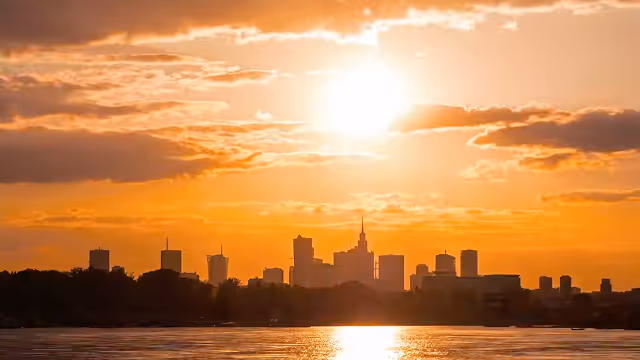 City skyline silhouette at sunset with sun reflecting on the water.