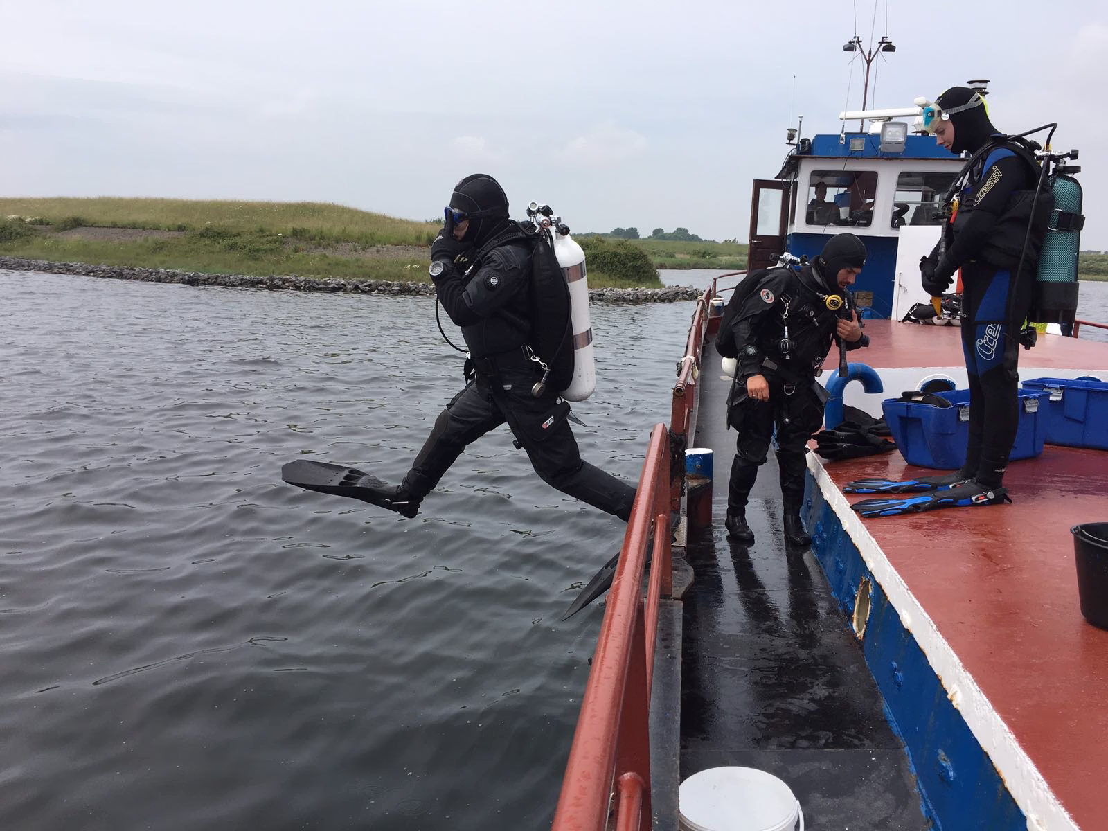 Man zit op het strand met een droogpak aan.