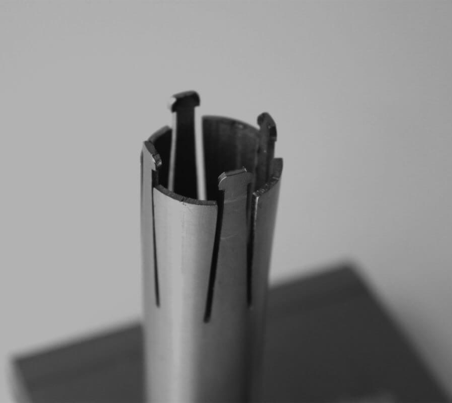 Close-up van een metalen spreidkraag met open spleten en grijpers aan de bovenkant.
