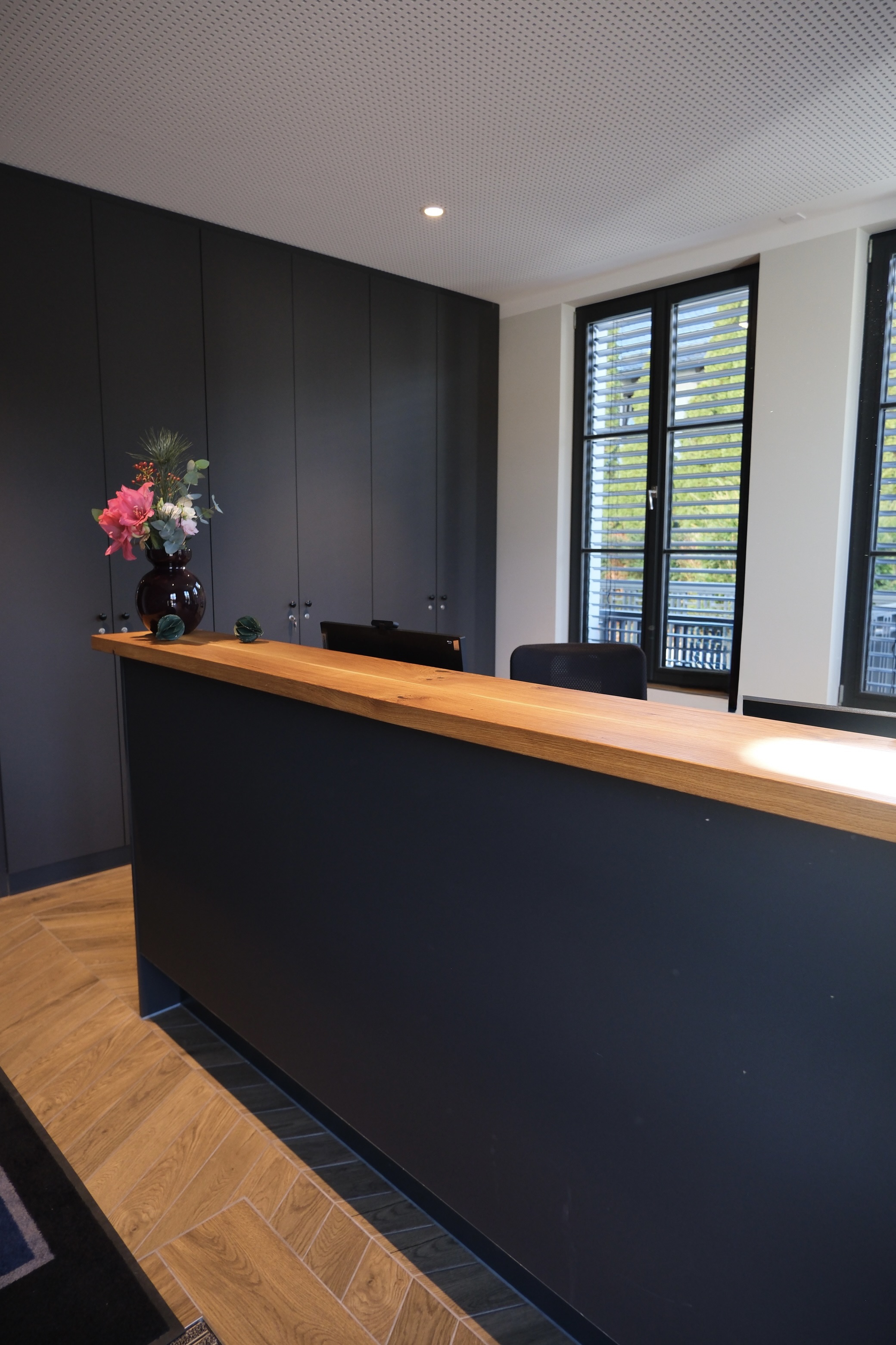 Eine große Anthrazitfarbene Rezeption im Eingangsbereich des Büros.