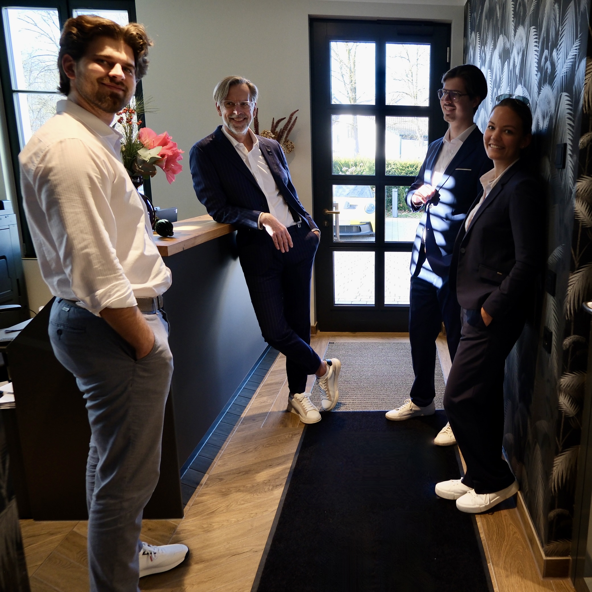 Das Team der Foresight GmbH Insurance Risk Advisory lehnt entspannt am Tresen des Eingangsbereichs ihres Büros.