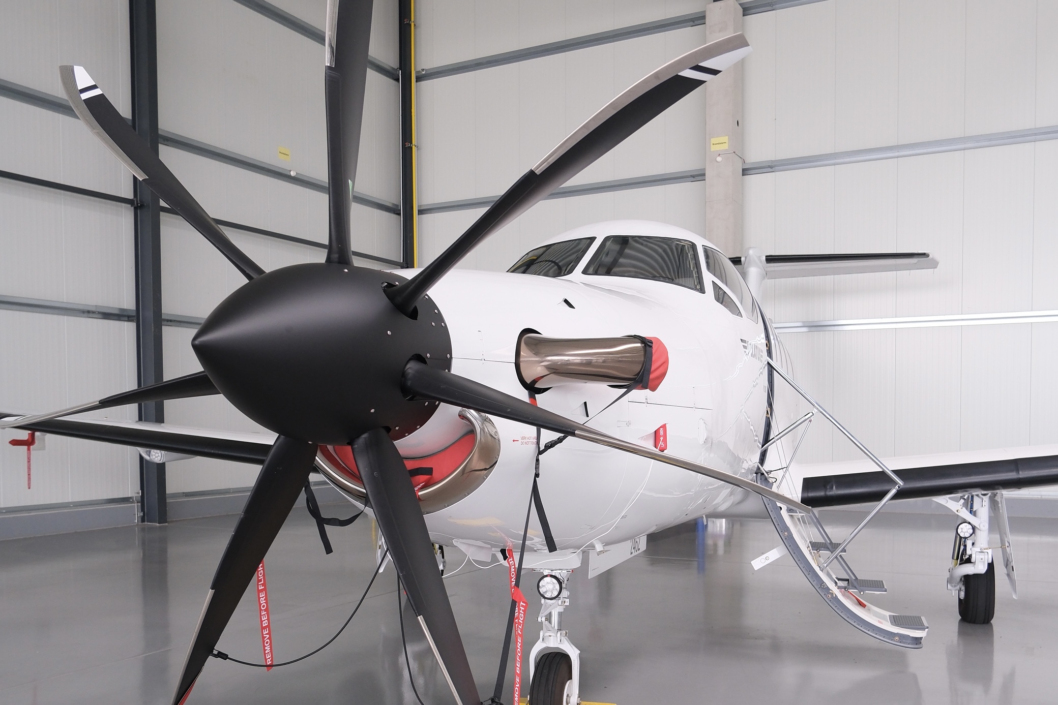 Ein Privat-Jet mit großem Propeller am Bug, der in einem Hangar steht.