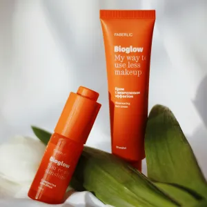 orange bottle and tube of hair conditioner surrounded by green leaves on a white background