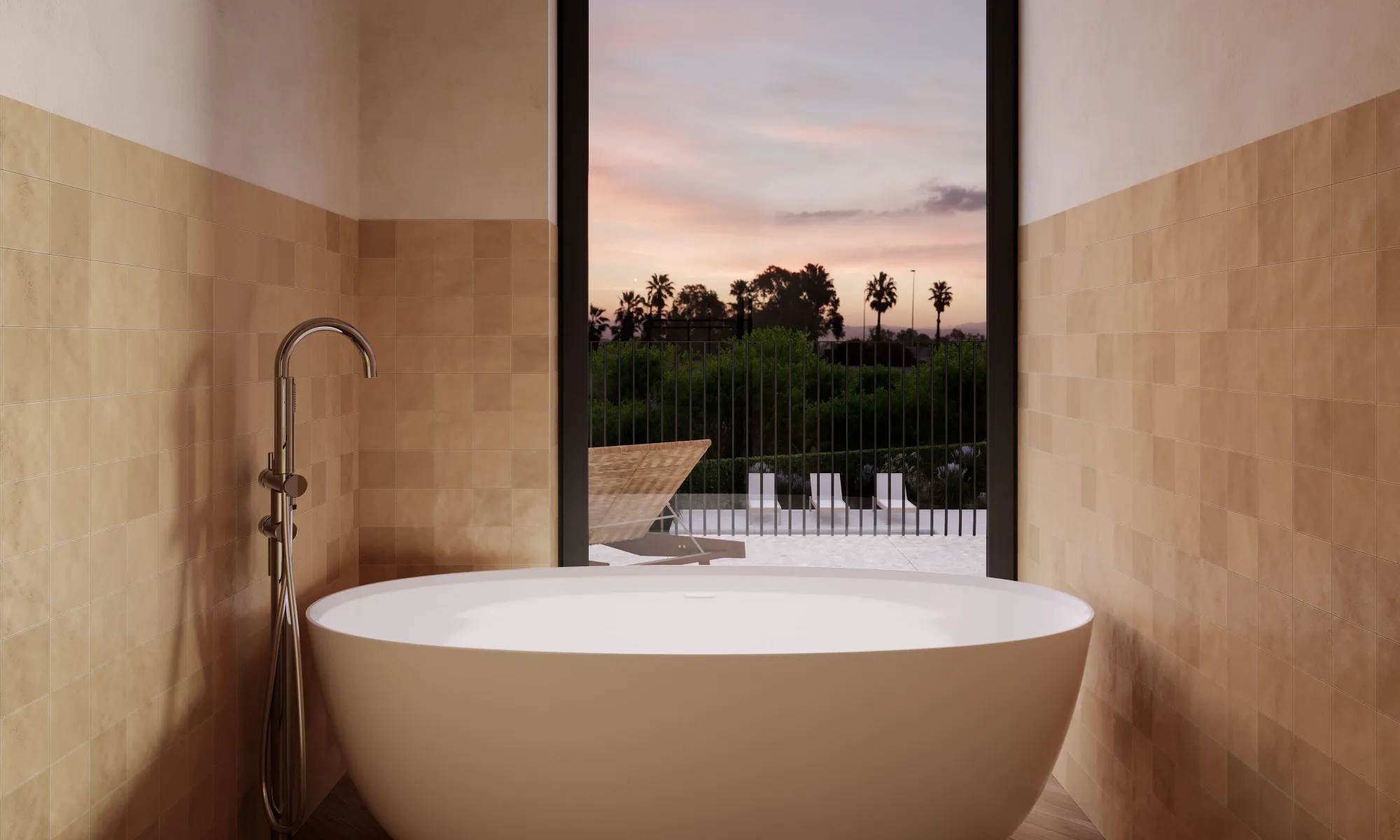 Modern white freestanding bathtub with chrome faucet, beige tiled walls, and a large window showing outdoor lounge chairs and palm trees at sunset.