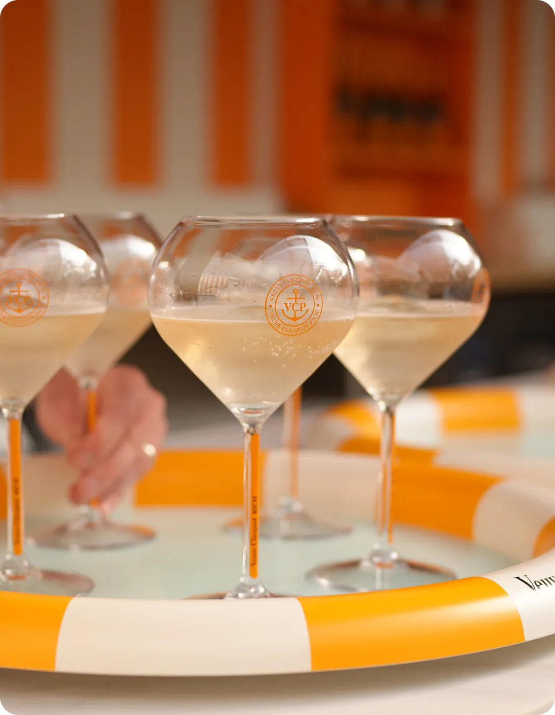 Glasses of Veuve Clicquot champagne served in a pool with an orange and white Veuve Clicquot branded float.