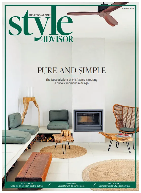 Minimalist living room with green cushioned seating, a modern fireplace, wooden rustic tables, wicker chair, ceiling fan, and natural woven rugs.