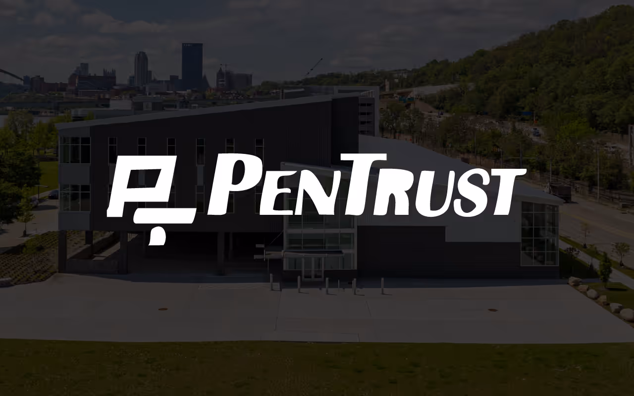 Modern building with large white PenTrust logo overlay and city skyline in the background.