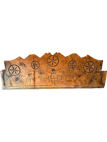 Wooden bench backrest with five carved circular star patterns and engraved inscriptions including a cross symbol.