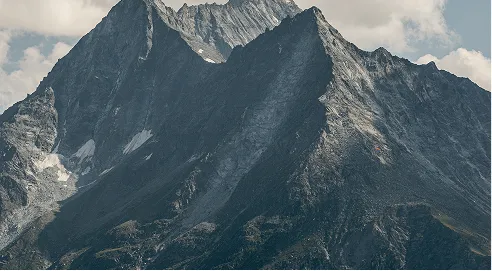 Steep rocky mountain peaks under a partly cloudy sky.