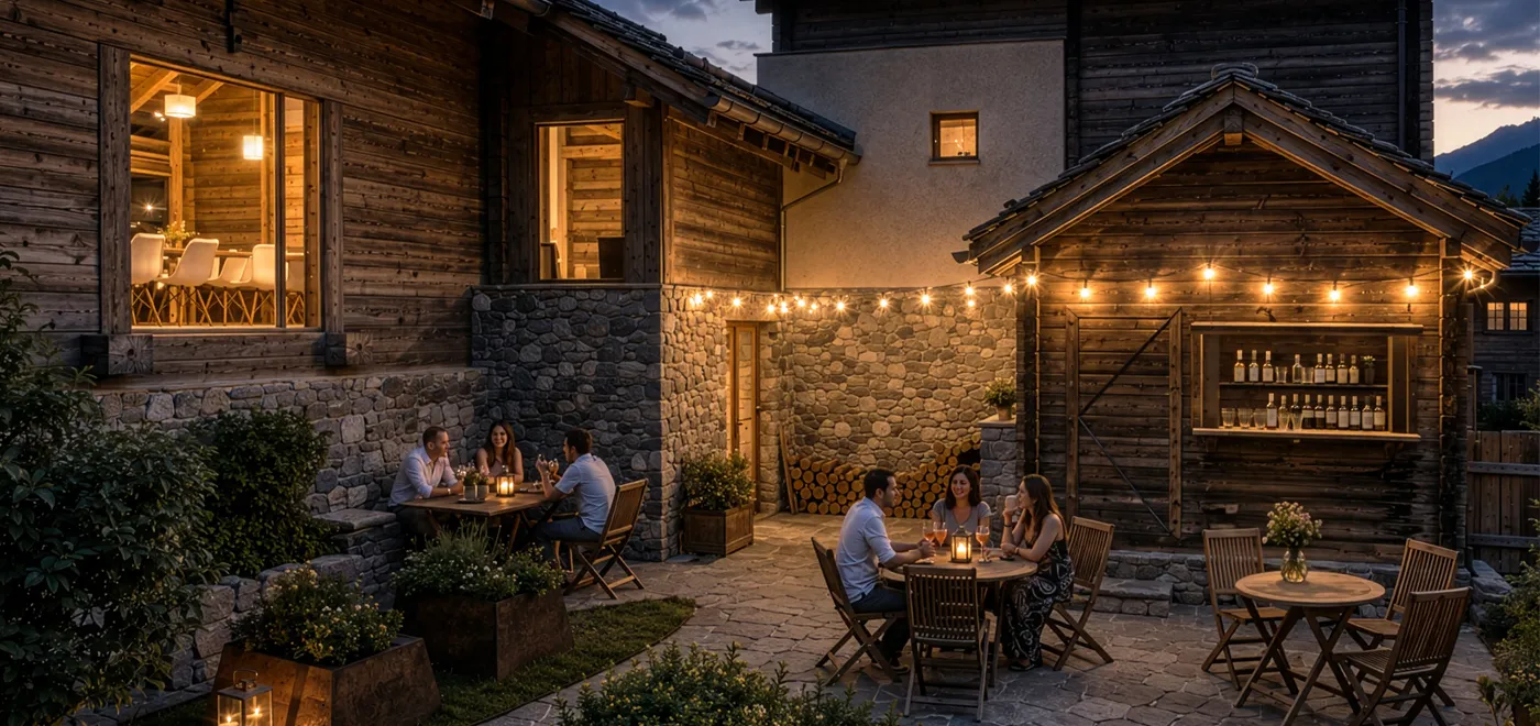 People sitting at outdoor tables in a cozy stone and wood courtyard lit by string lights at dusk.