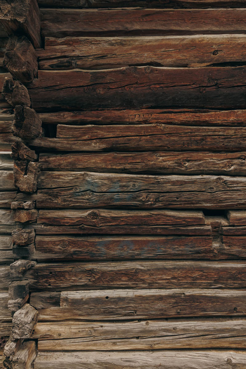 Close-up of a weathered wooden log wall with visible grain and knots.