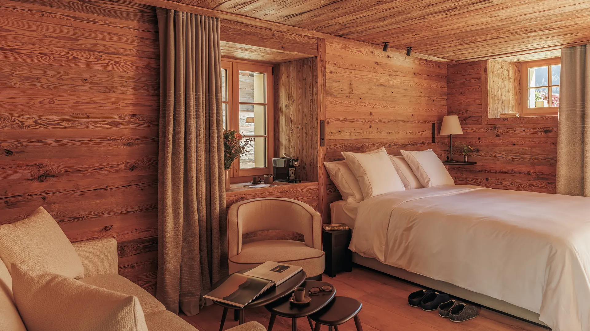 Barma room with a double bed, armchairs and nested coffee tables in a fully wood-panelled alpine interior