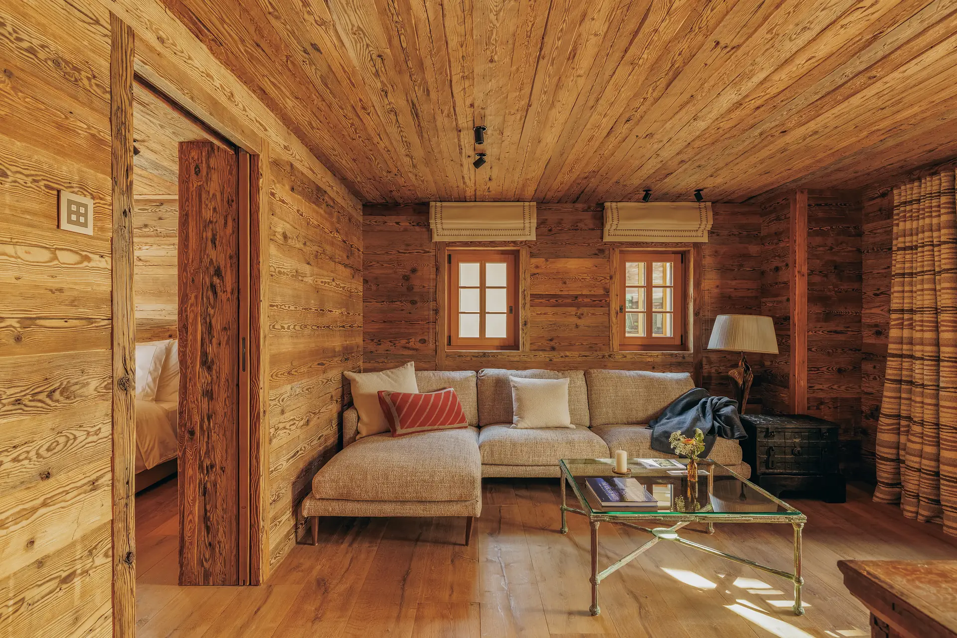 Wood-paneled living area with a sectional sofa and glass coffee table