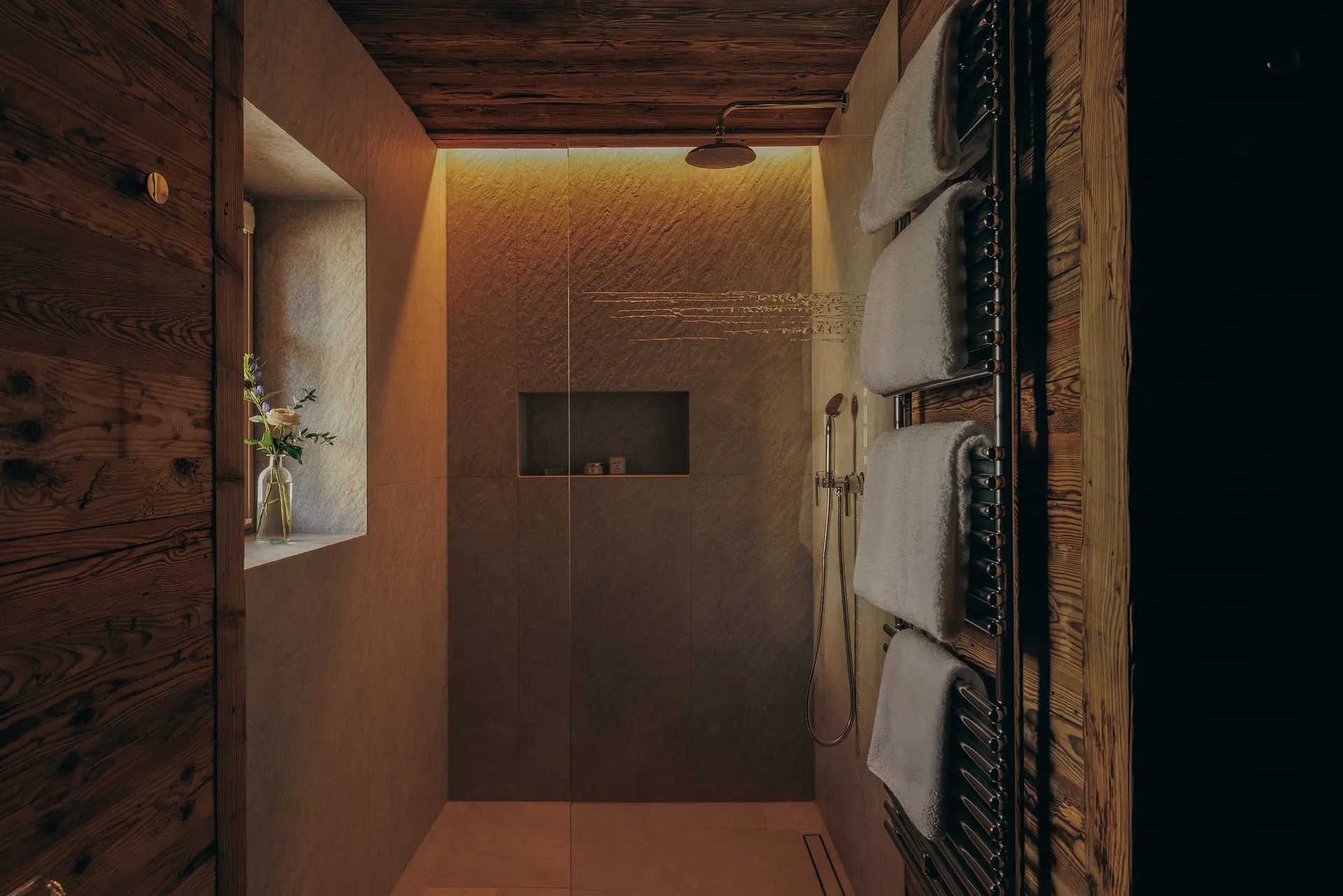 Walk-in shower with a rain showerhead and folded towels on a heated rail