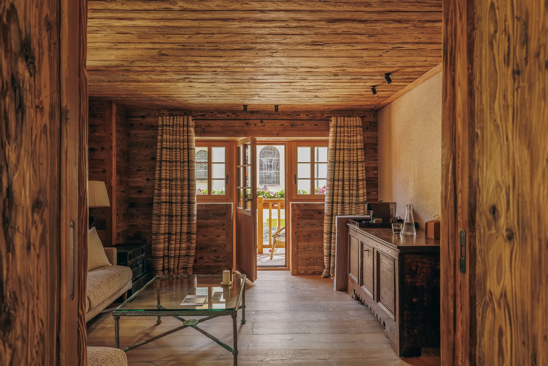 Wood-paneled sitting area with an open door leading to a flower-lined balcony