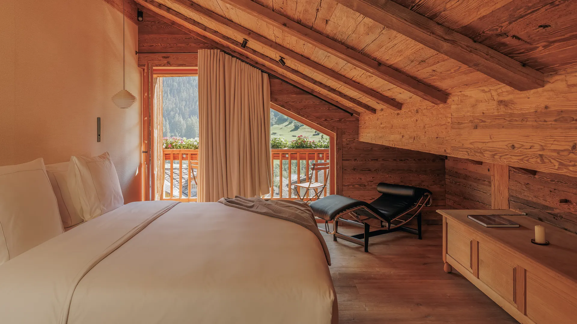 Byenyo bedroom overview with double bed, chaise longue, balcony opening and a winter forest print on the log wall