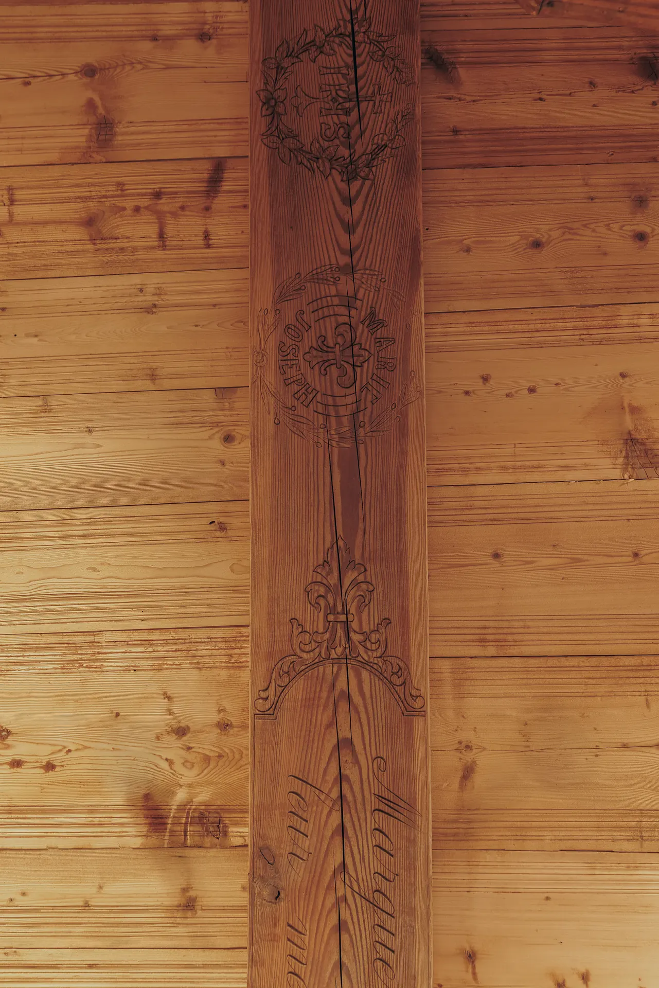 Detail of an engraved ceiling beam with floral motifs and the inscriptions Marie, Joseph and Marguerite
