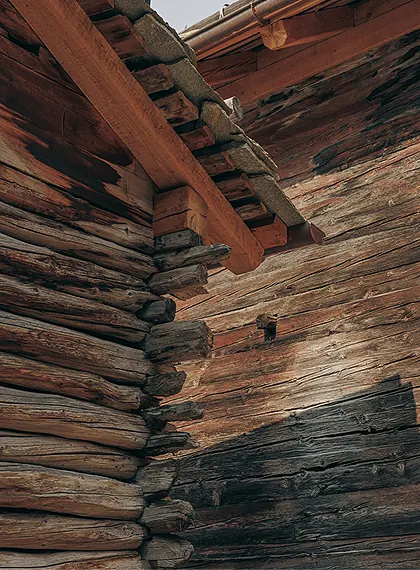 Close-up of weathered interlocking log corner joints on the exterior of a traditional alpine chalet