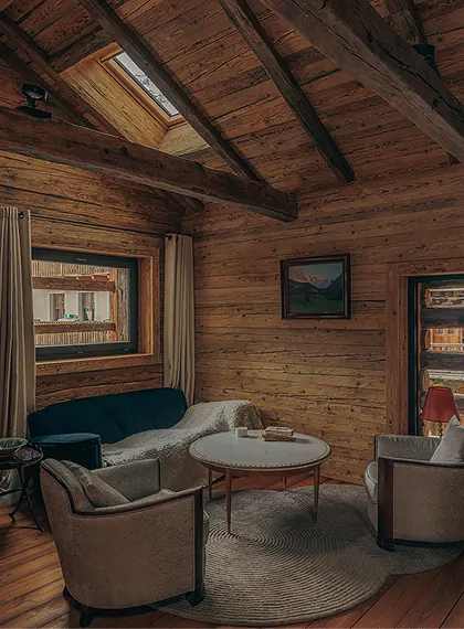Cosy chalet sitting room with a teal sofa, round coffee table, an oil painting and a roof skylight