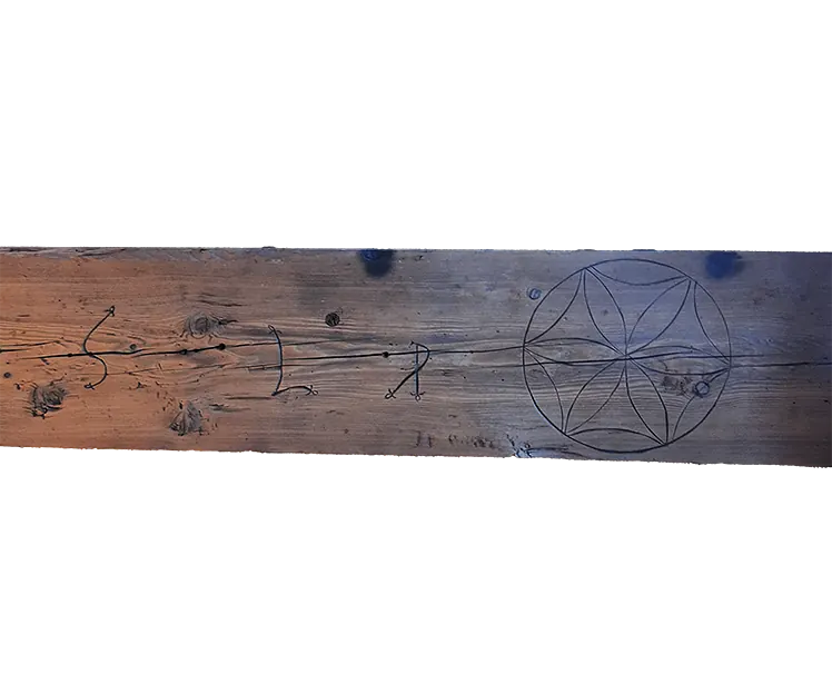 Wooden plank carved with a flower-of-life symbol and initials
