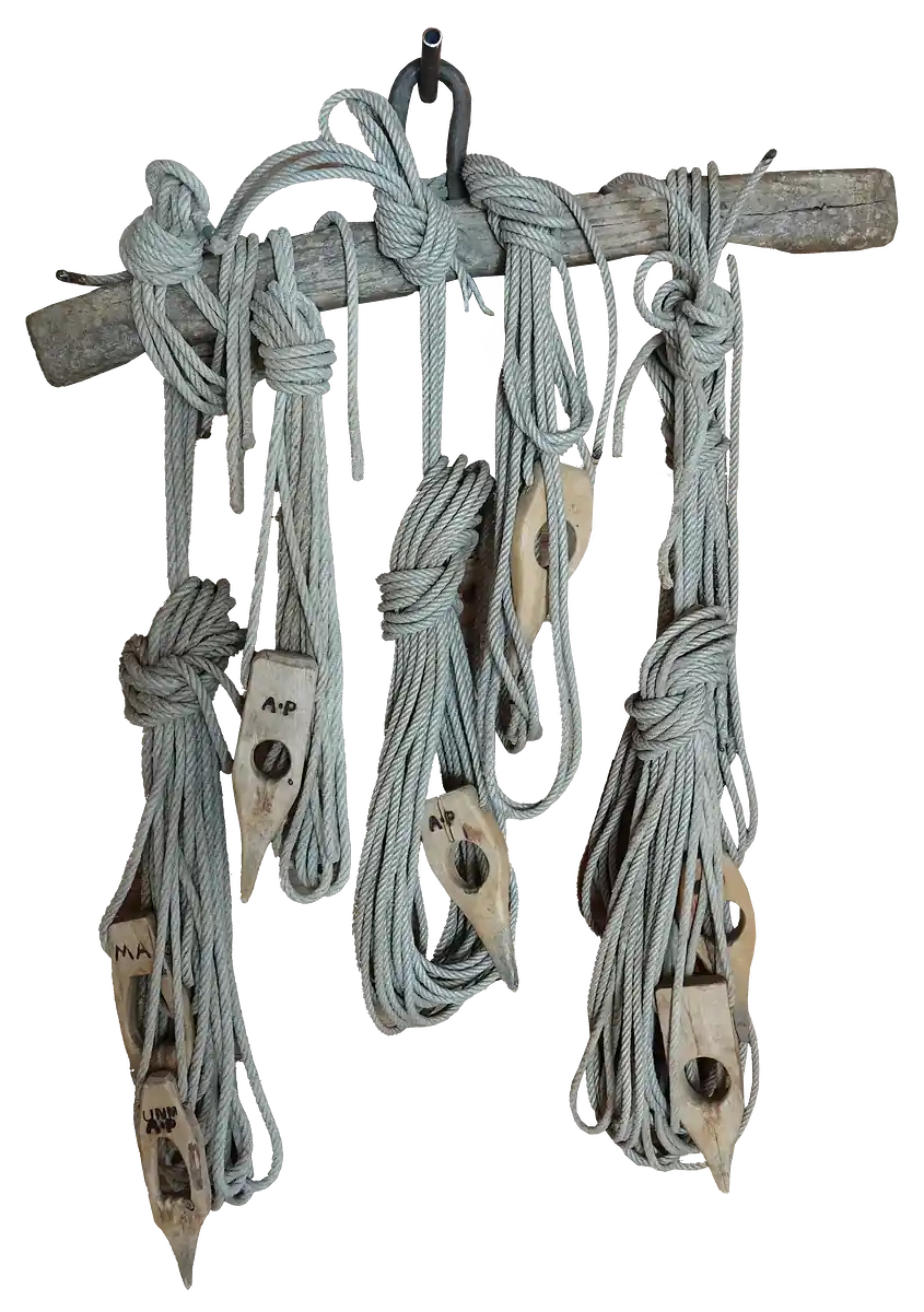 Set of wooden pulley blocks and coiled ropes hanging from a bar