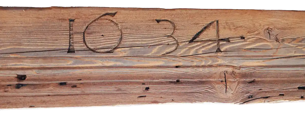 Close-up of a wooden beam carved with the date 1634