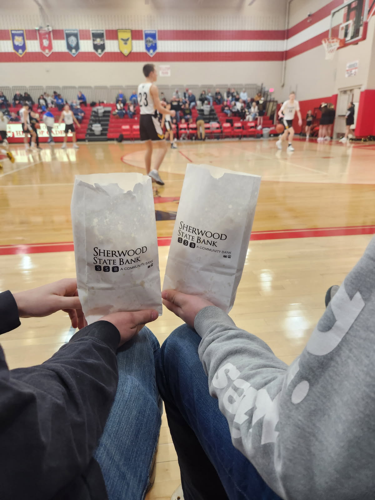 Group of twelve people standing in front of Sherwood State Bank holding a blue ribbon for a ribbon-cutting ceremony.