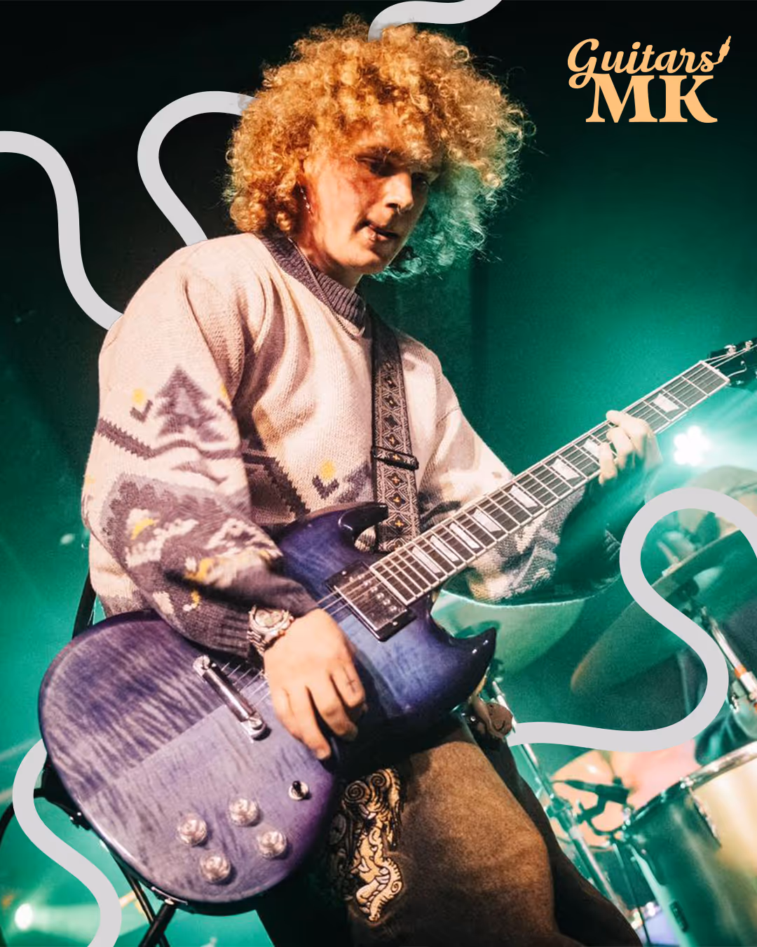 Guitarist with curly hair performing live on stage with a blue electric guitar, surrounded by curved white lines — Guitars MK logo top right.