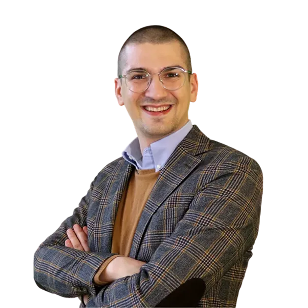 Smiling man with glasses wearing a plaid blazer and brown sweater, arms crossed.