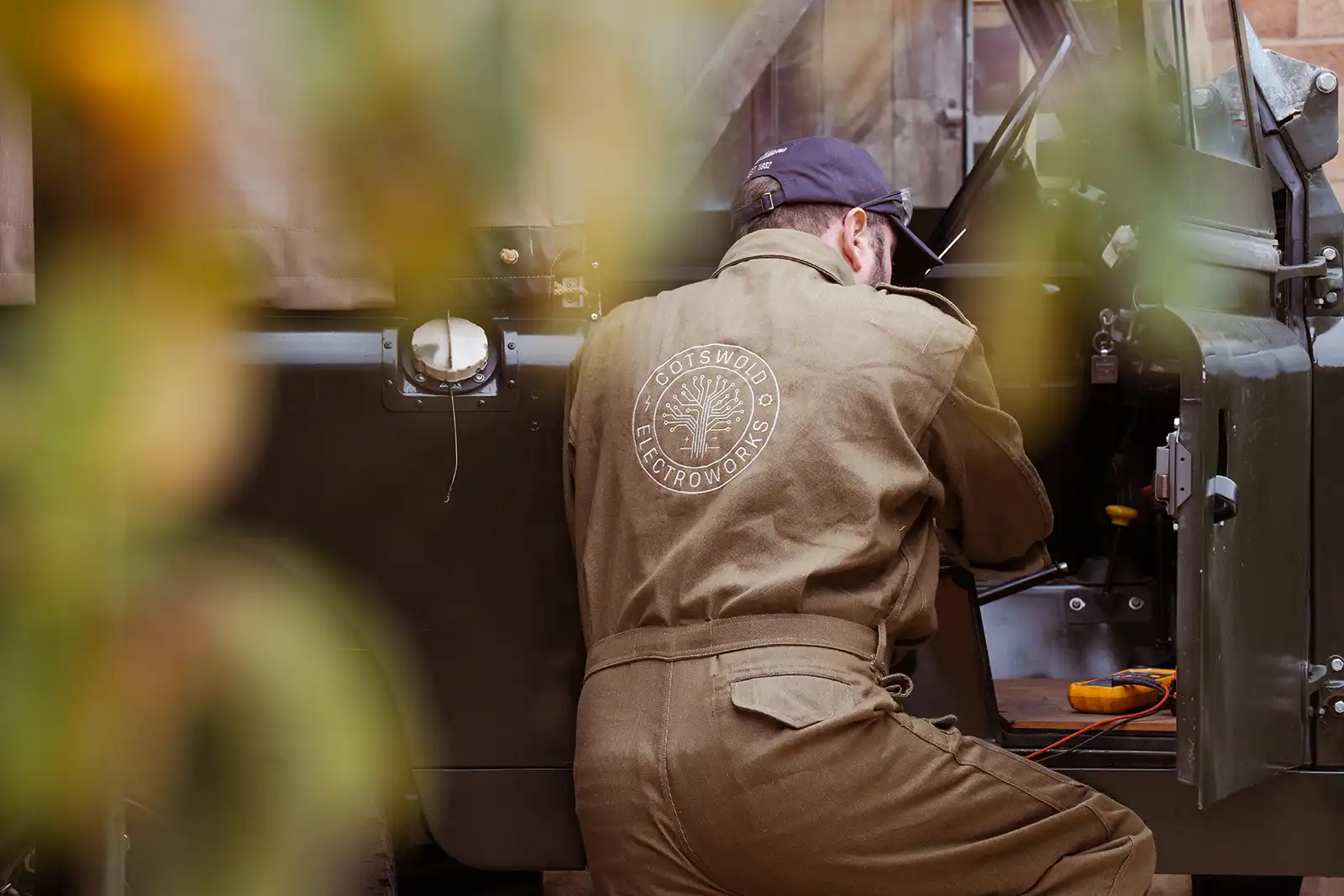 Technician in brown uniform works on electrical equipment at Cotswold Electroworks