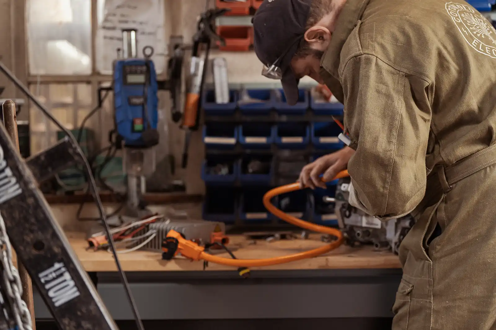 Electrician working with orange cables and tools in workshop