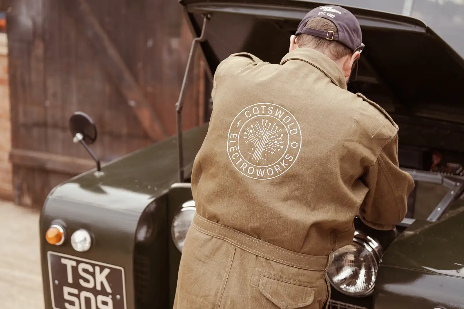 Worker in Cotswold Electroworks jacket standing near vintage vehicle