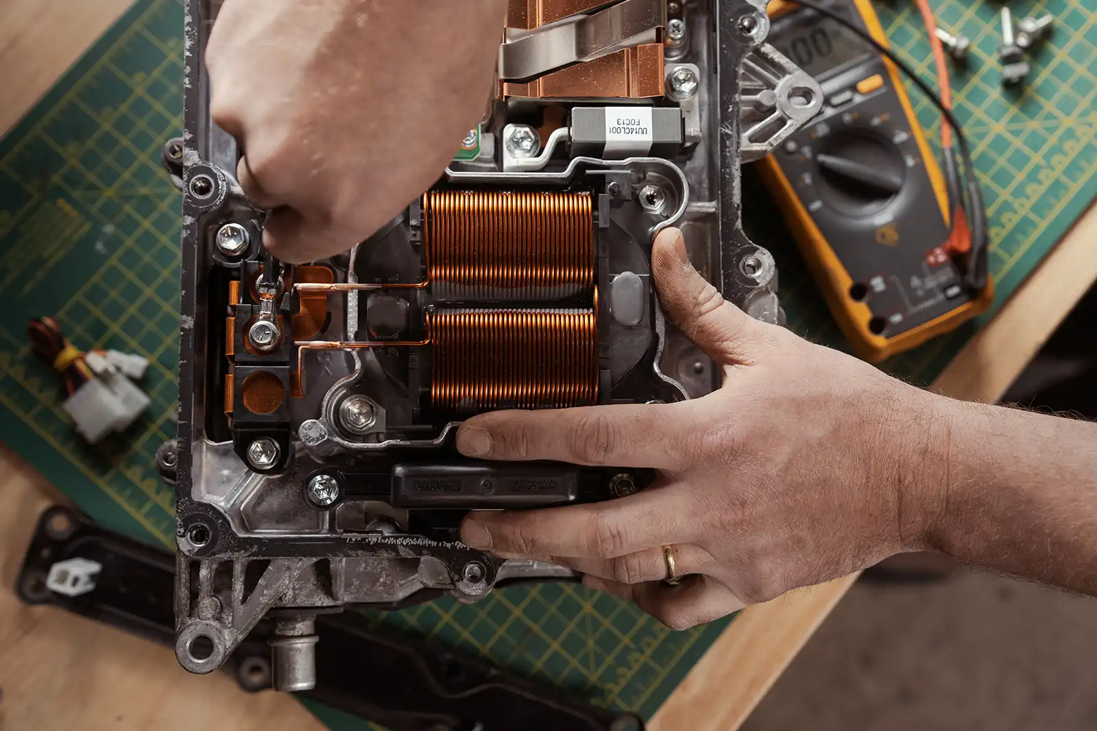 Hands repairing electronic device with copper coils and mechanical components