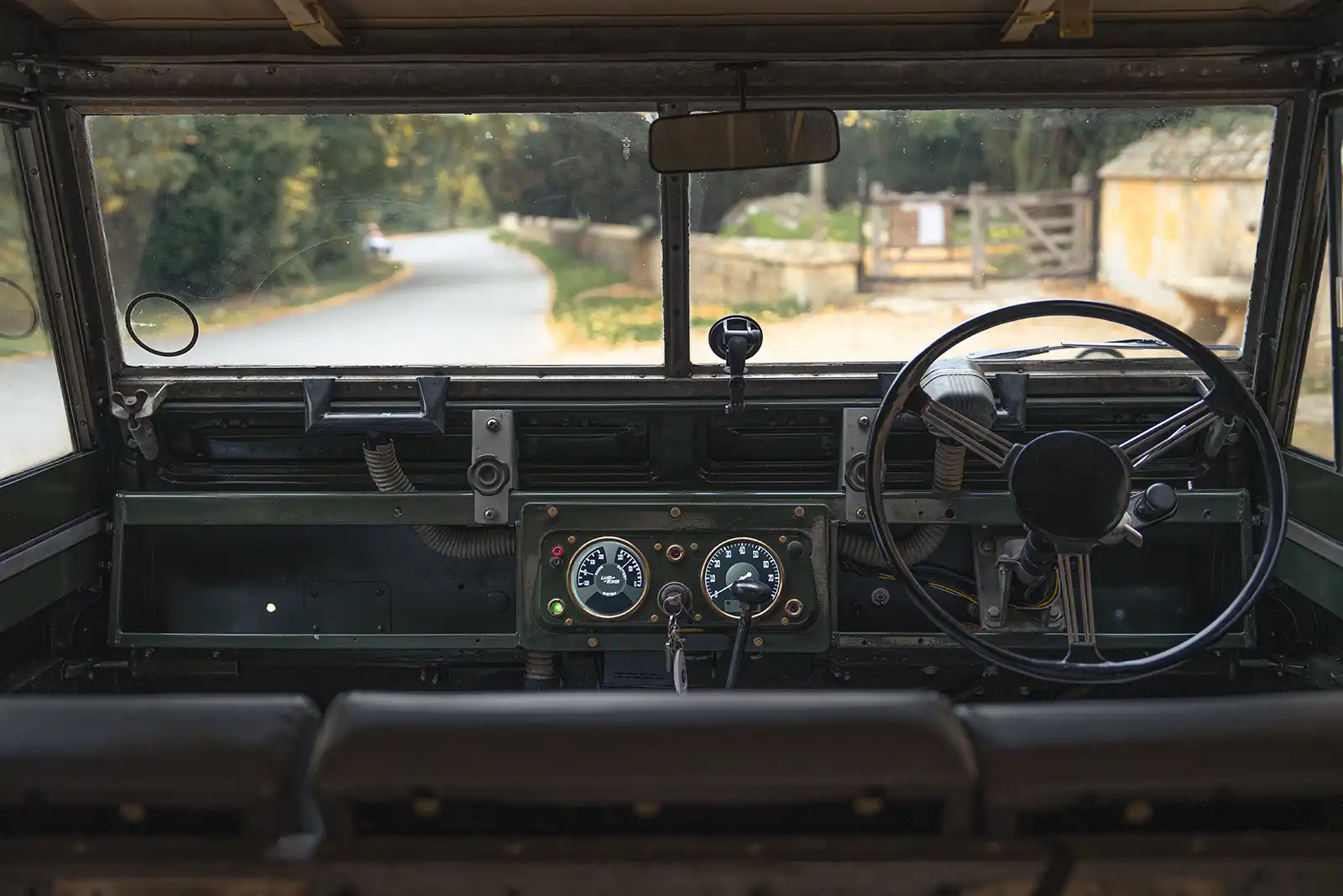 Classic Land Rover interior view with rural road through windshield