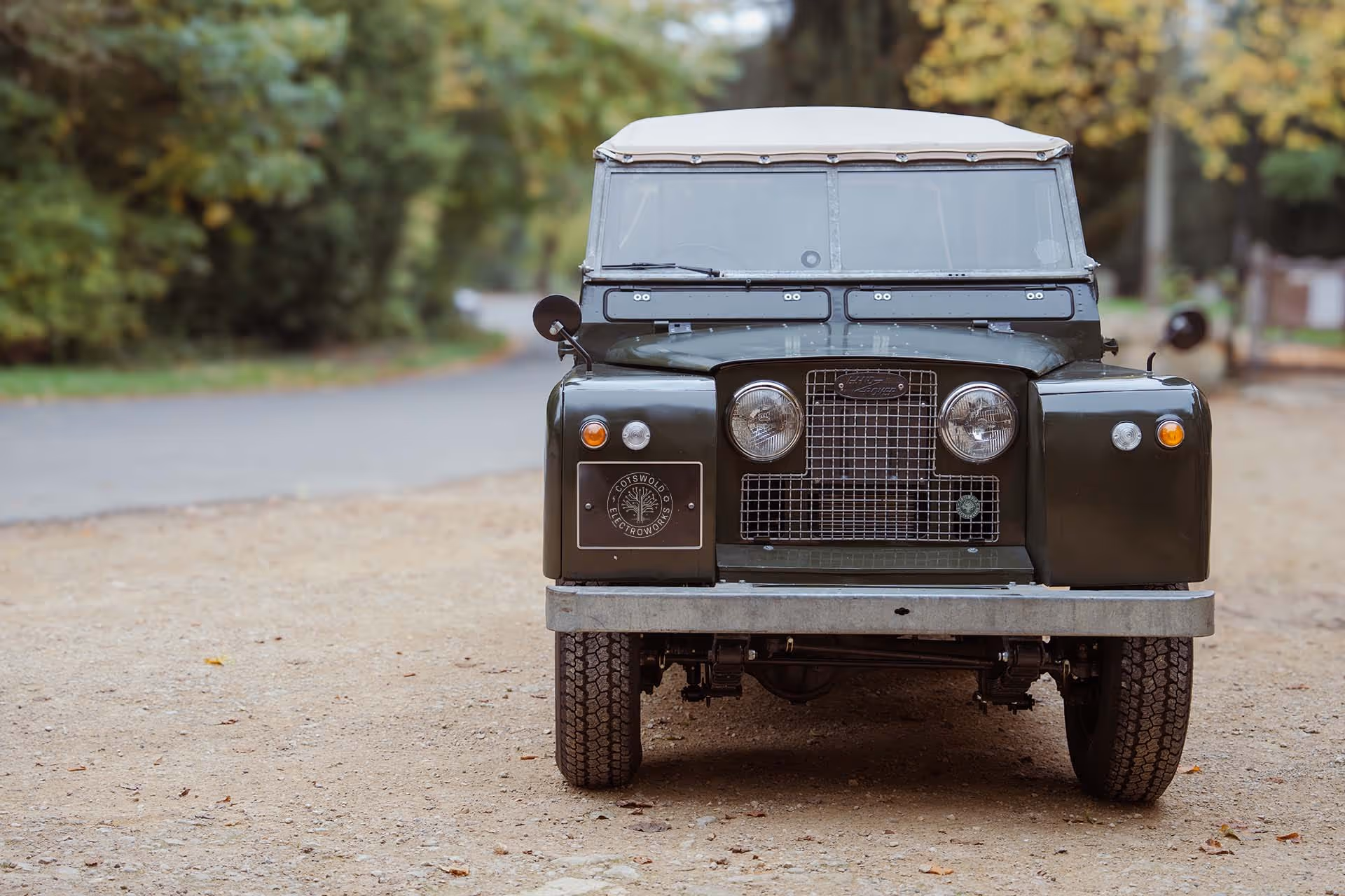 Vintage Land Rover Series II parked on gravel road surrounded by trees