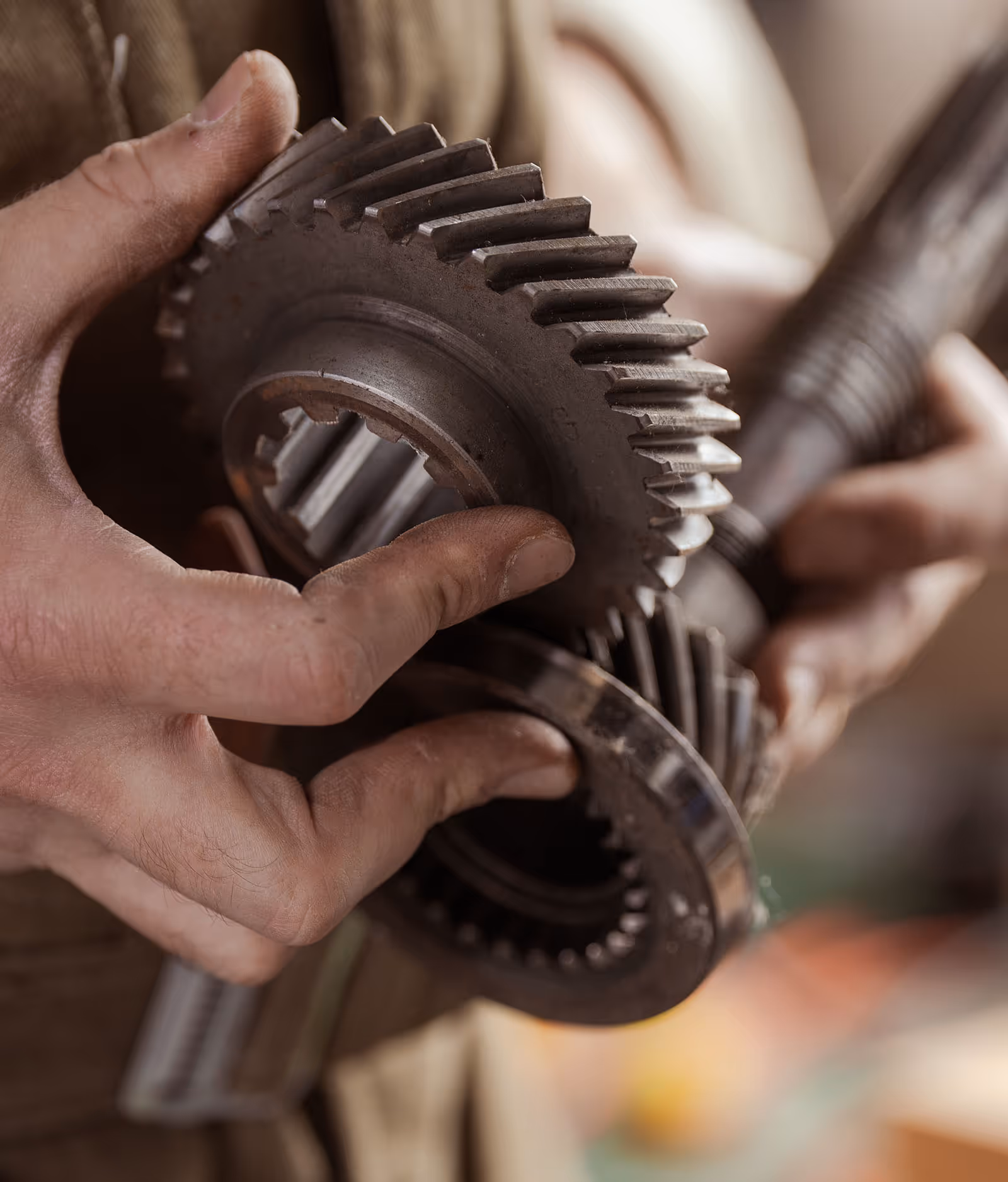 Hands inspecting large metal gear mechanism in mechanical workshop