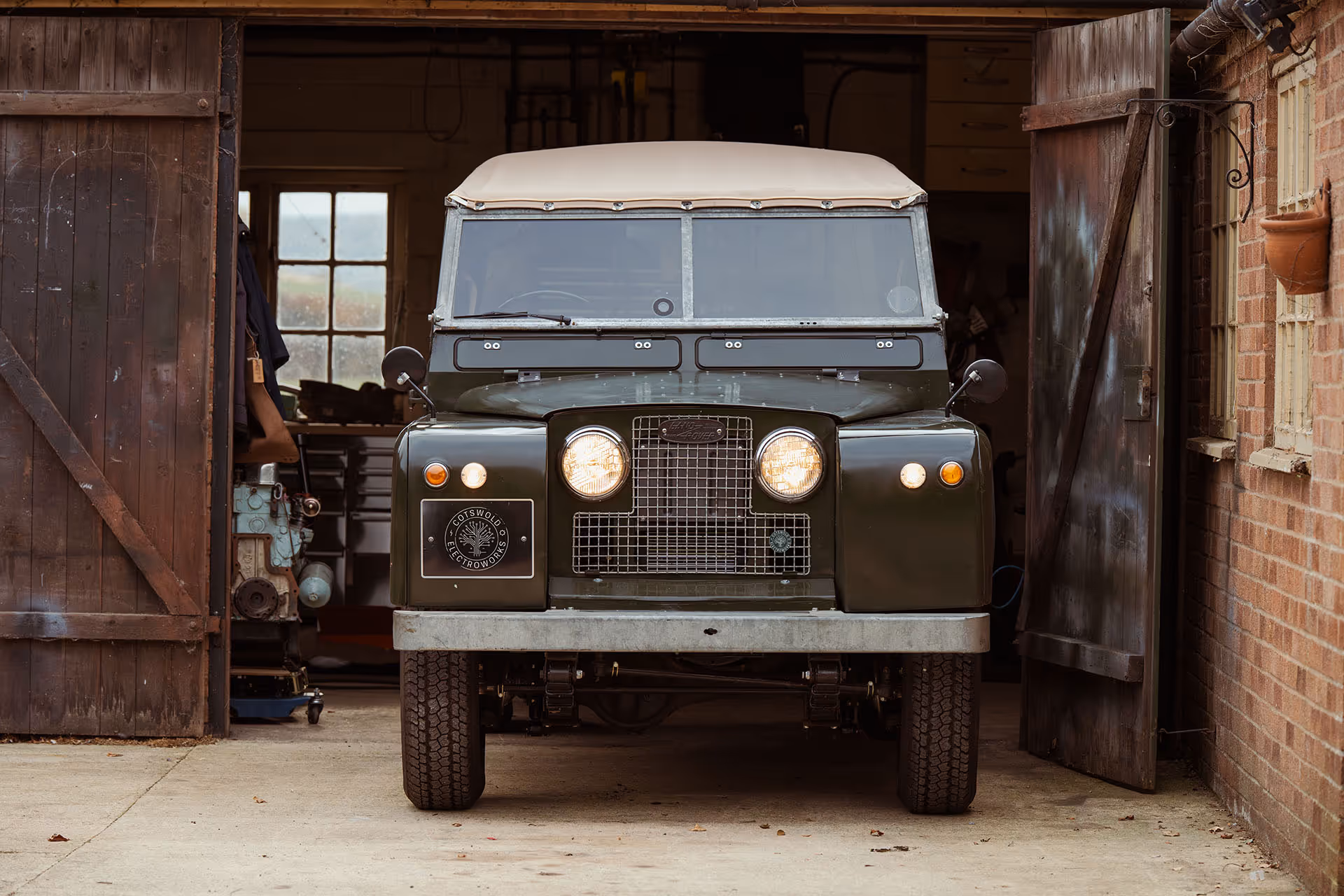 Classic green Land Rover parked inside a rustic wooden barn