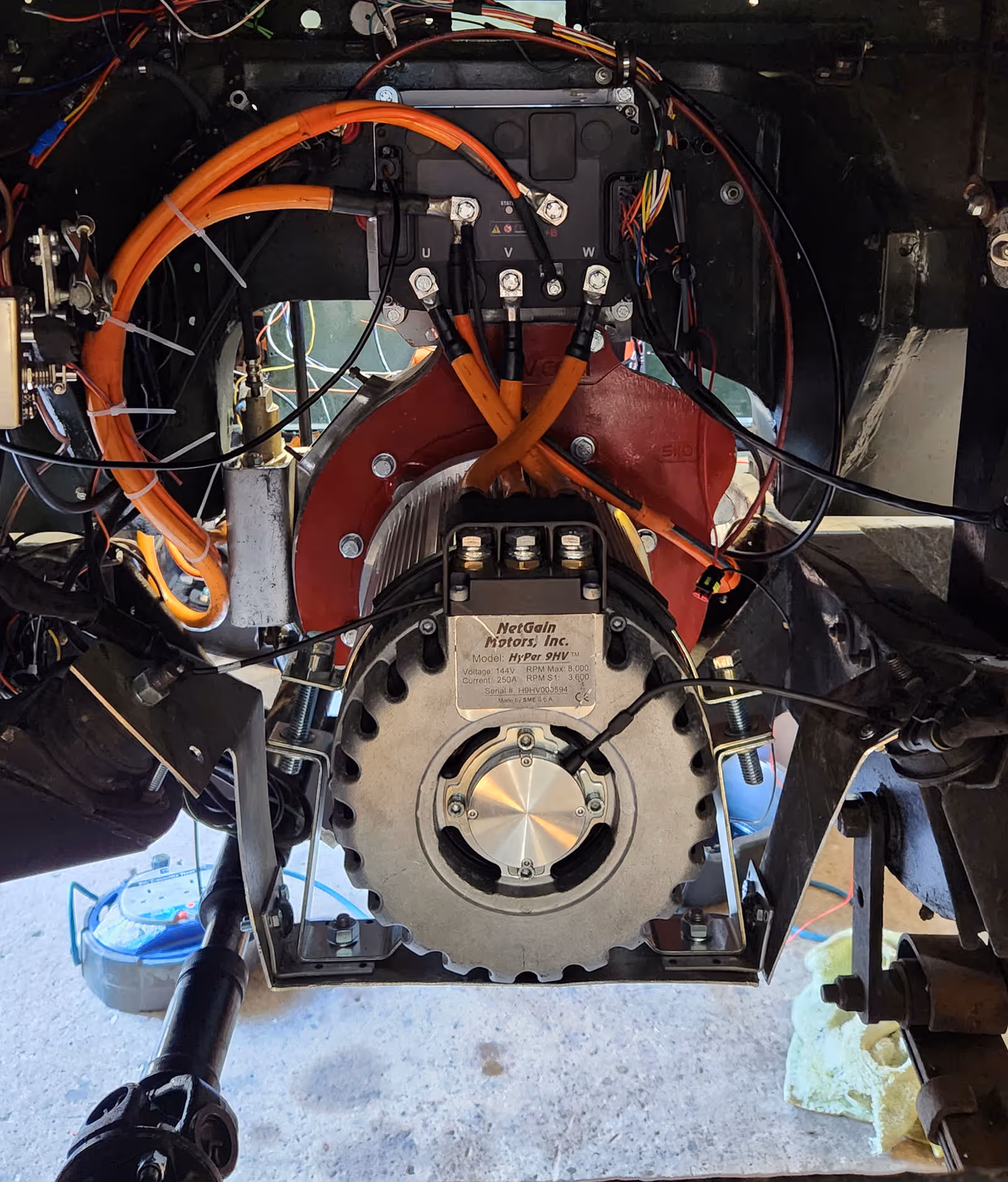 Close-up of a NetGain Motors HyPer 9HV electric motor with connected orange cables and mounting hardware.