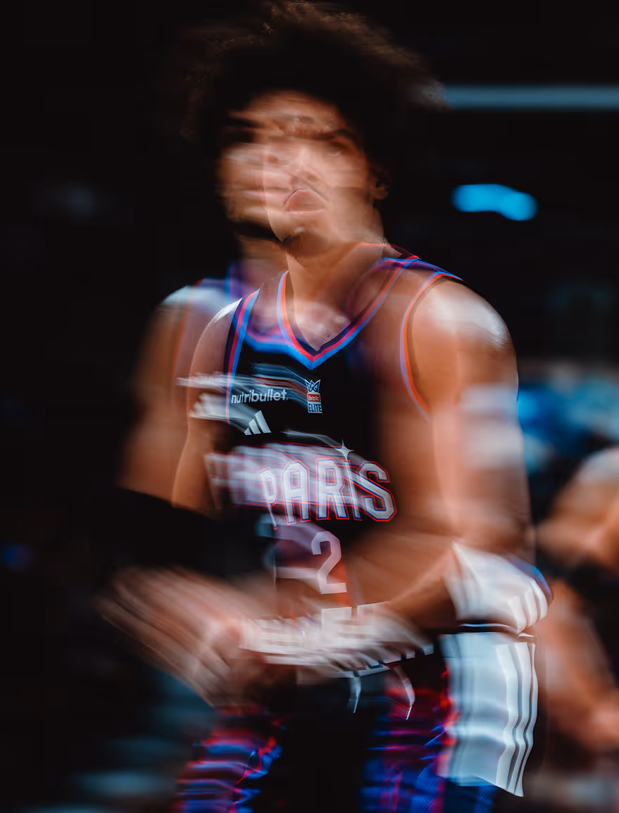 Blurred action shot of a basketball player wearing a dark jersey with the word 'SPARS' and the number 2.
