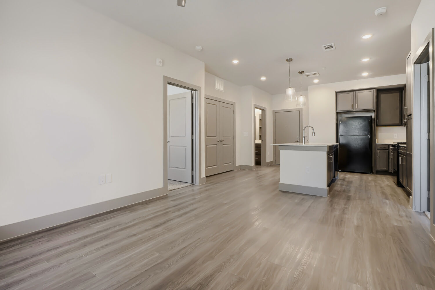 Unfurnished living area with view of Kitchen with island, brown cabinets and black appliances