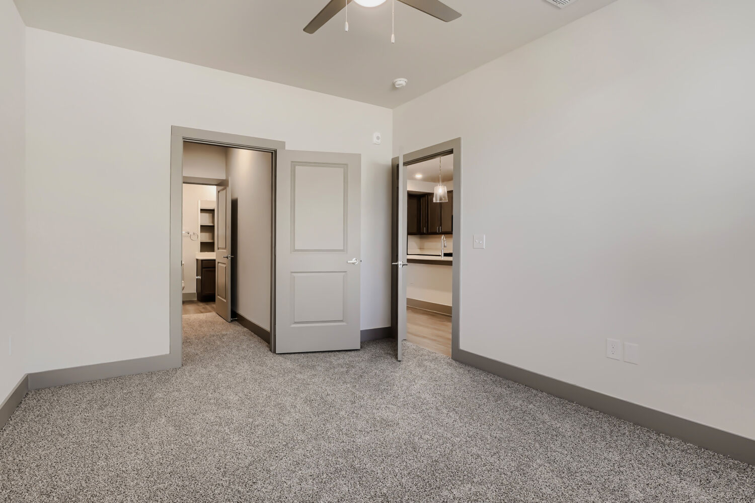 Unfurnished bedroom with view into bathroom and kitchen