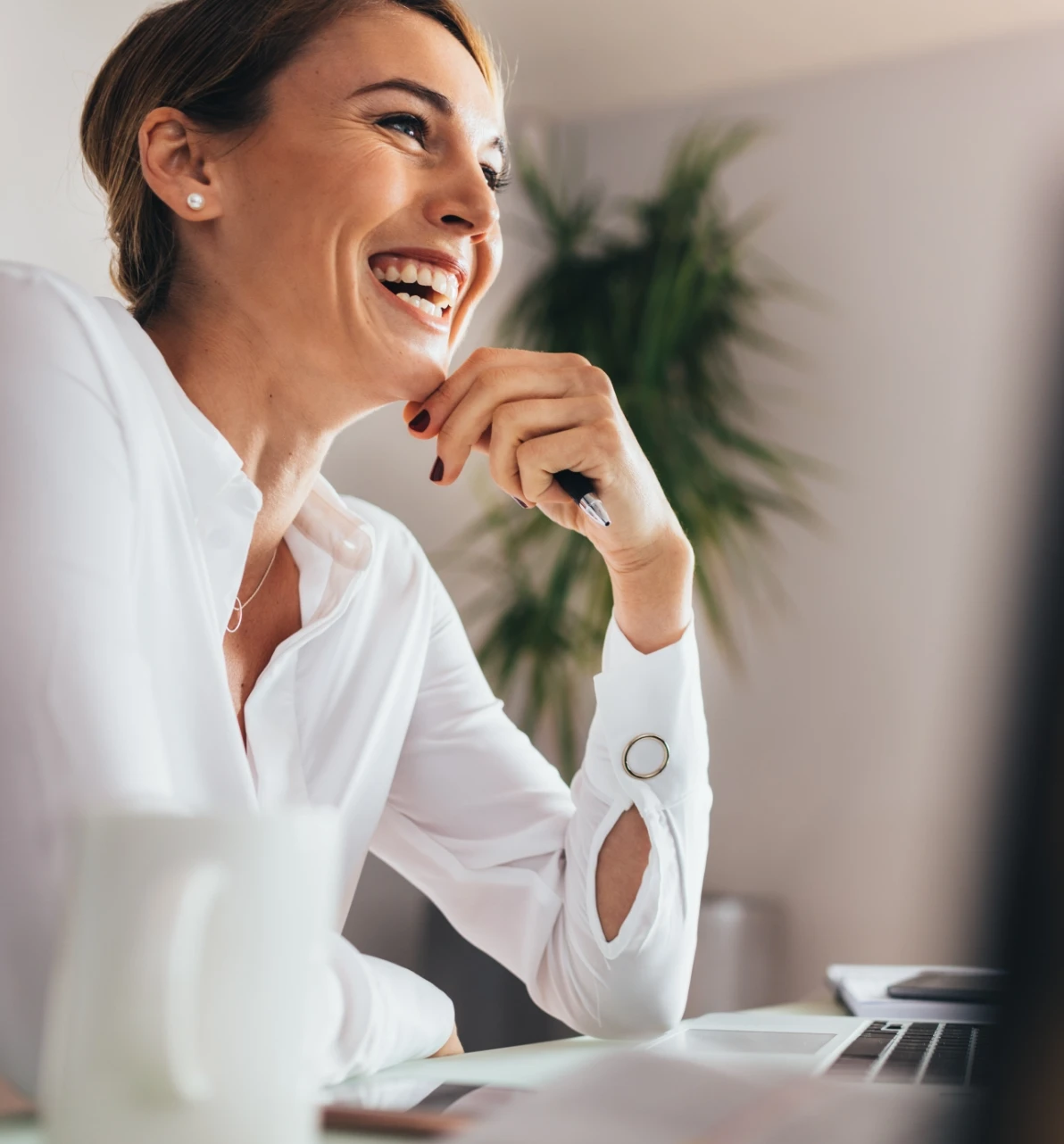 A smiling woman sitting at a desk with a laptop.