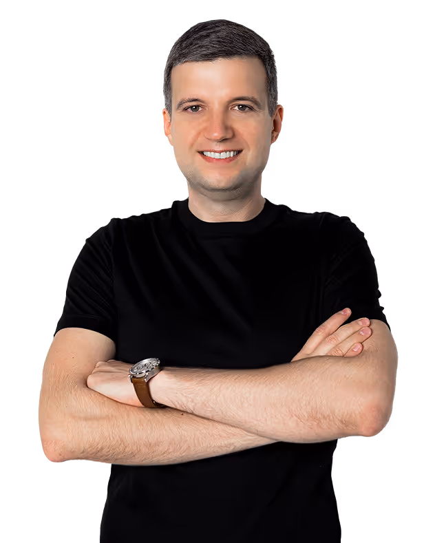 Smiling man with short dark hair wearing a black t-shirt and a wristwatch, standing with arms crossed.