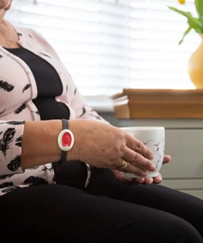 Person wearing a white medical alert bracelet holding a white marble-patterned mug.