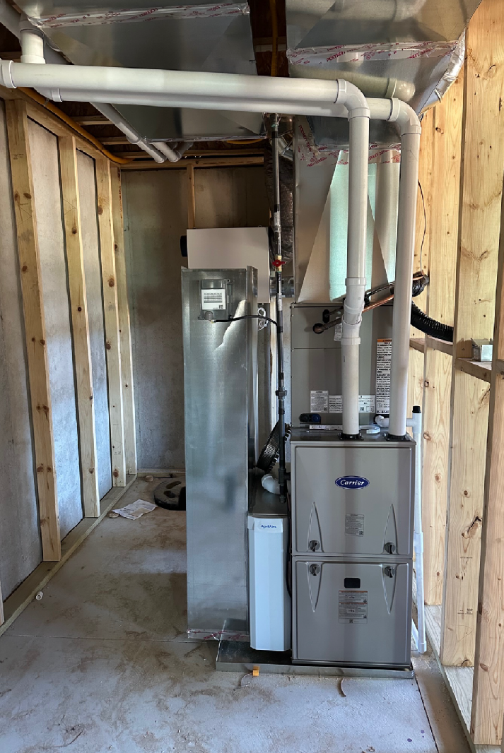Heating, ventilation, and air conditioning (HVAC) unit installed in an unfinished basement with exposed wooden framing and concrete floor.
