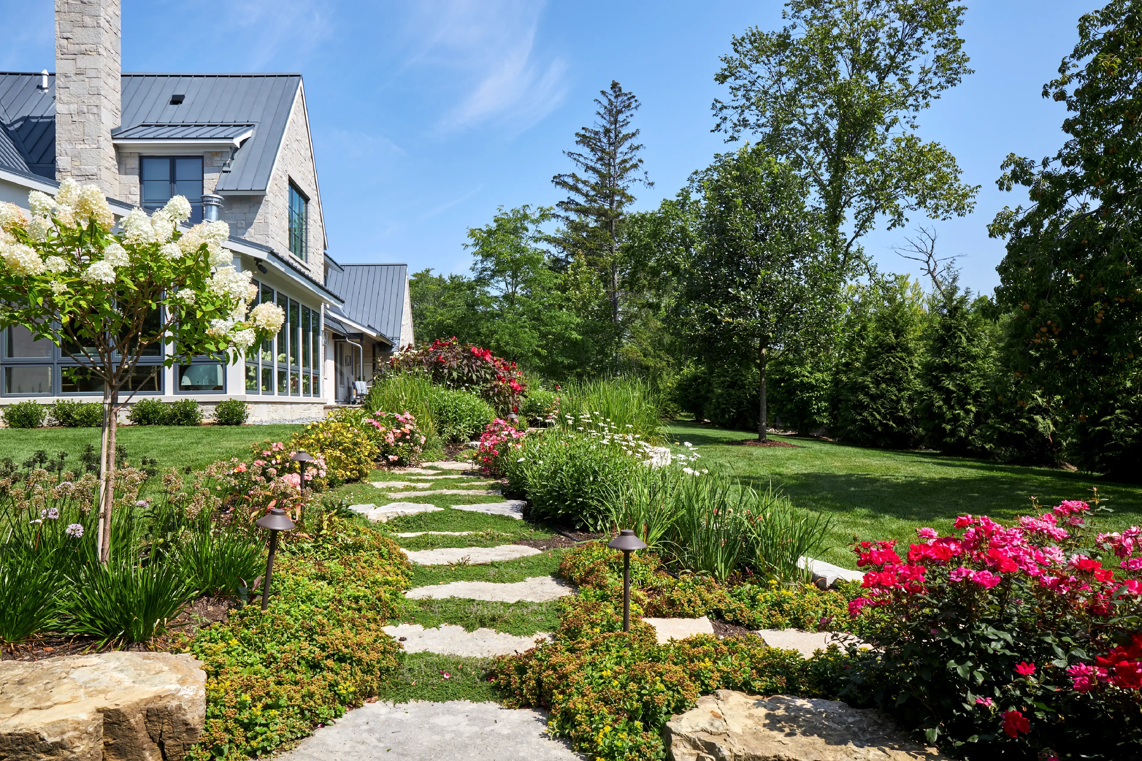 Well maintained stone walkway with flowers and bushes on either side
