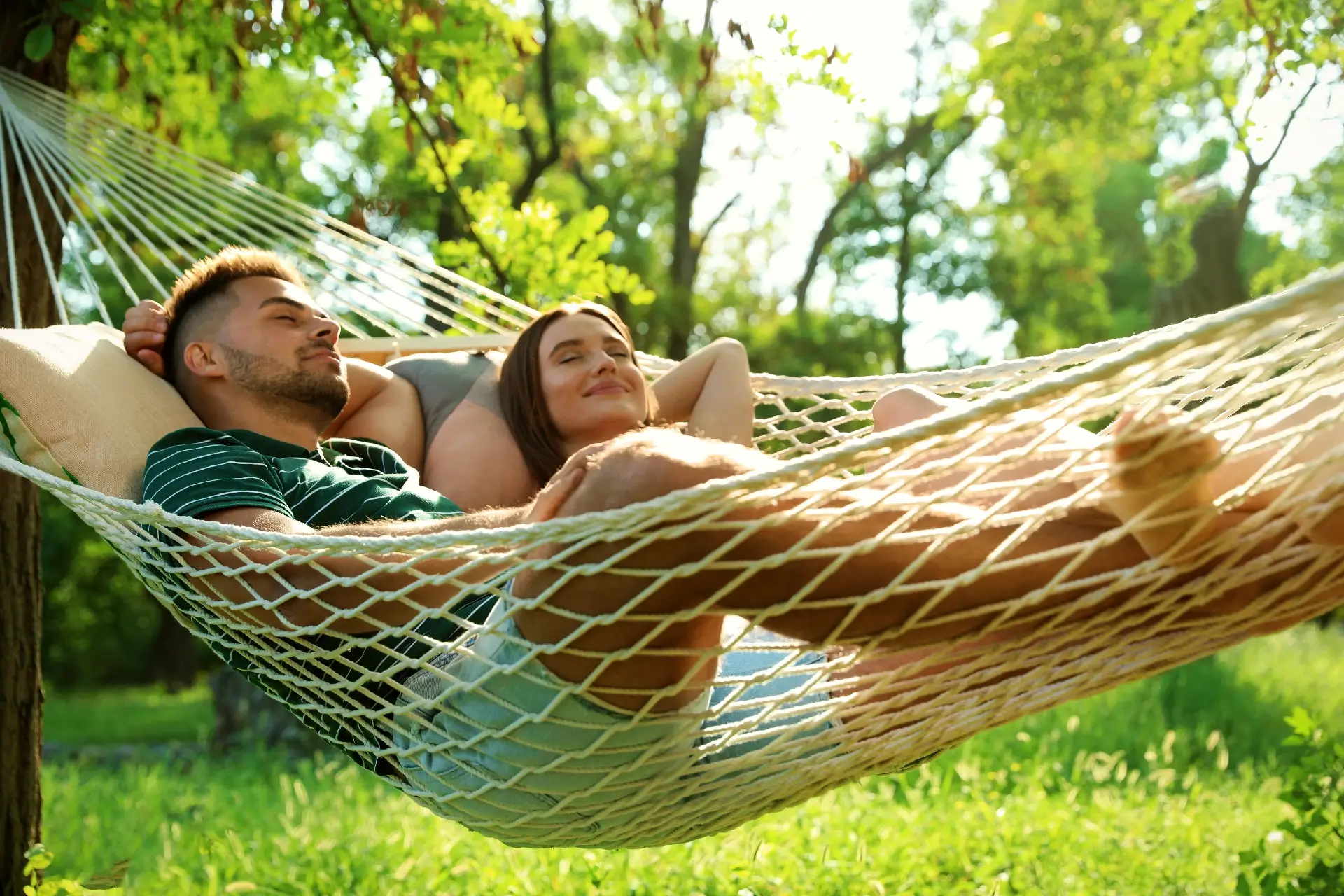 Young couple resting in comfortable hammock at green garden