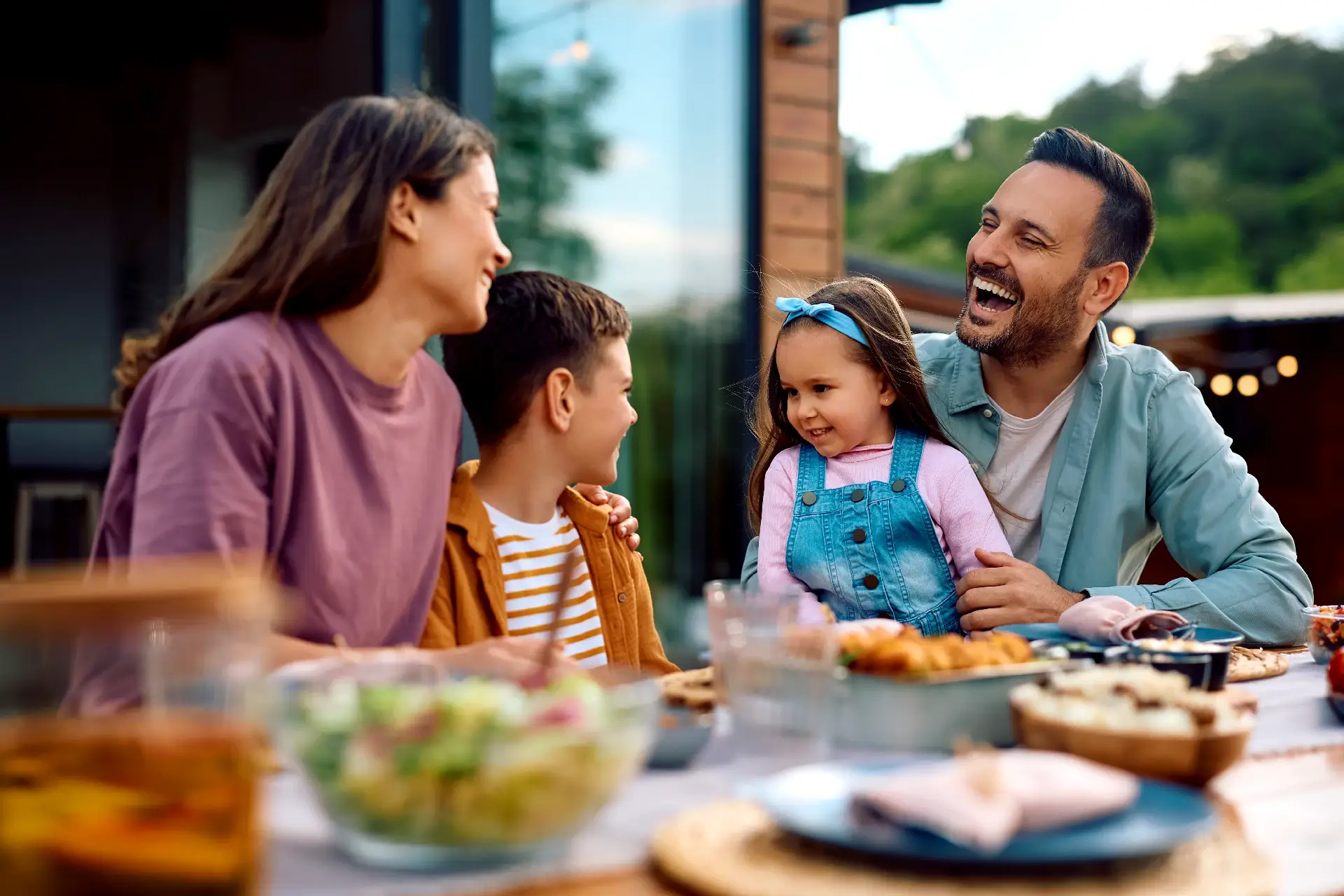 Cheerful family having fun while communicating during a meal on their terrace.