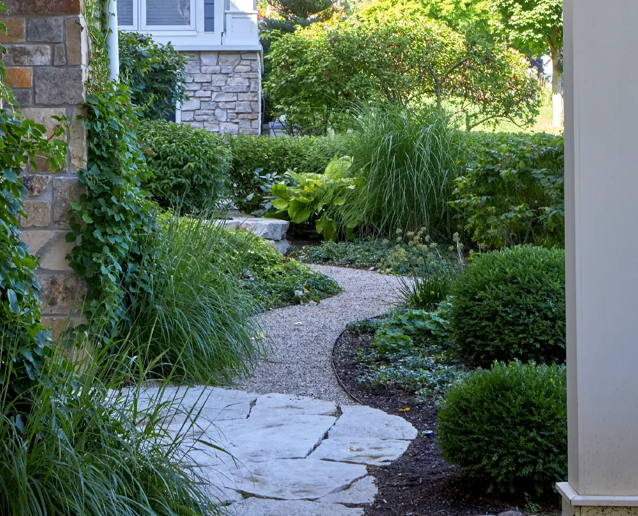 Winding pathway leading through front yard surrounded by bushes